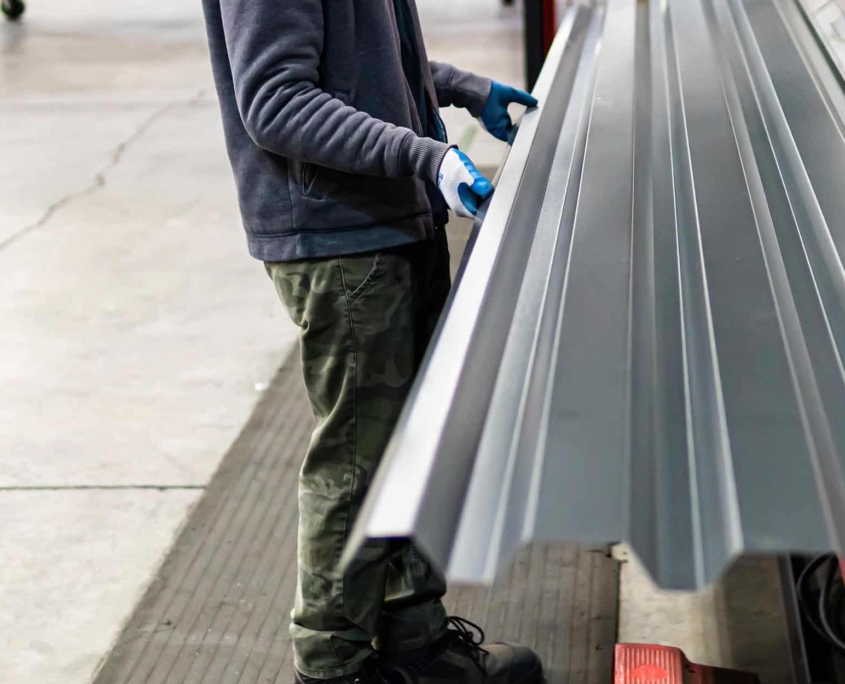 Worker Bending Metal Sheets For Roof